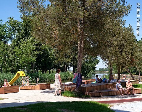 Flussfreibad Oettingen Blick auf Sitzgelegenheiten im Flussfreibad. Links im Hintergrund sieht man eine Rutsche.