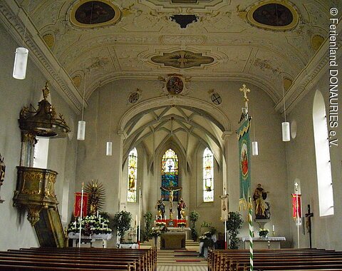 Innenansicht Pfarrkirche St. Peter und Paul, Unterschneidheim Blick auf den mit Blumen geschmückten Innenbereich mit dem Hauptaltar, zwei Seitenaltären und der Kanzel links im Bild.