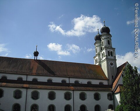 Außenansicht der Pfarrkirche Mariä Himmelfahrt mit ihren zwei Türmen und ihren vielen Fenstern.