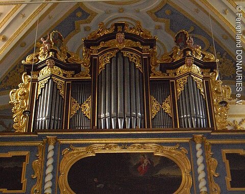 Blick auf die Empore mit der gold- und silberfarbenen Orgel