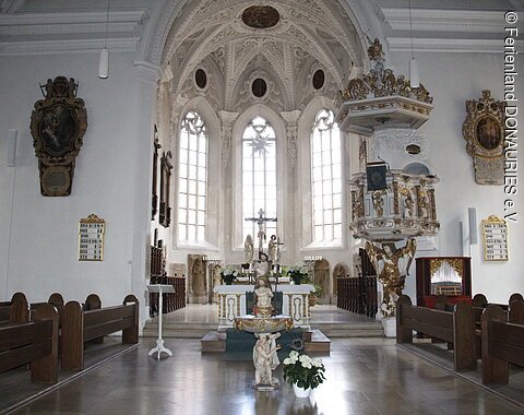 Blick in den hellen Innenraum auf den Altar mit rechts daneben liegender Kanzel.