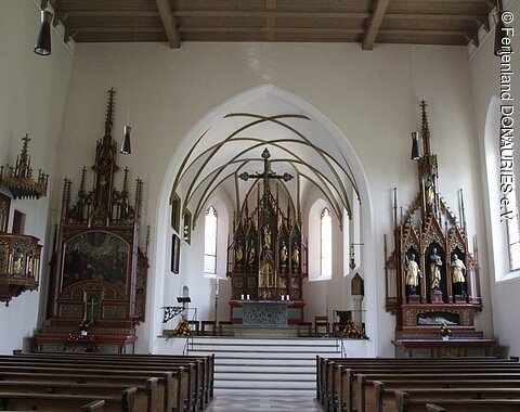 Blick auf das schlichte Innere von St. Sebastian. Vorne in der Mitte der Hauptaltar. Rechts und links im Bild die beiden Seitenaltäre sowie ganz vorne links im Bild die Kanzel.