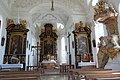 Blick in die helle, lichtdurchflutete Schlosskirche. Vorne in der Mitte der Hauptaltar, links und rechts die Seitenaltäre sowie ganz rechts im Bild die Kanzel.
