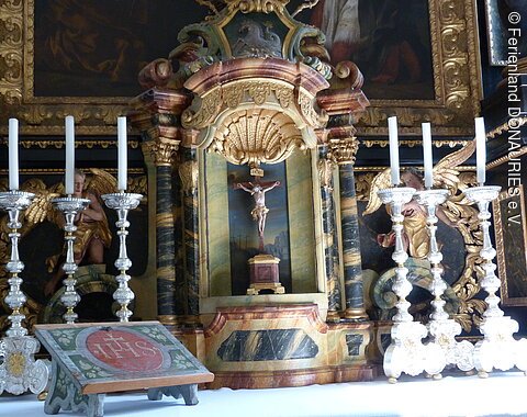 Altardetail - ein Kreuz umrahmt von Kerzen