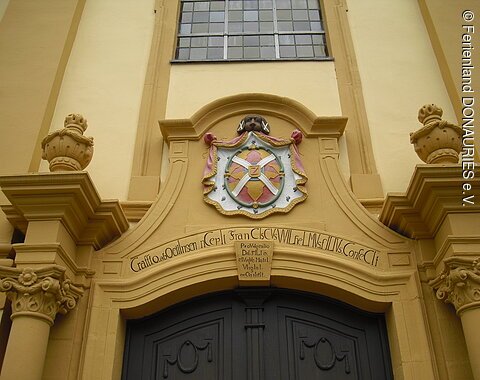 Blick auf das Eingangsportal mit Wappen über dem Tor.