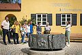 Eine Führerin zeigt den Führungsteilnehmern den Brunnen an der Tourist-Information
