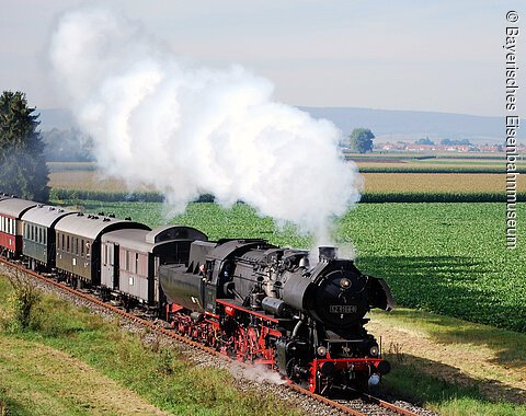 Dampfzugfahrt im Bayerischen Eisenbahnmuseum Eine Dampflokomotive mit Waggons fährt rauchend durch das Ries