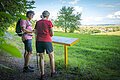 Zwei Wanderer studieren eine Infotafel mit Ausblick auf die herrliche Landschaft.