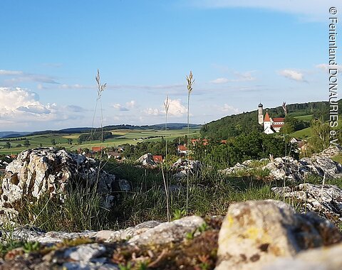 Blick vom Kühstein in Mönchsdeggingen auf den Ort und die Kirchen. Im Vordergrund sieht man das Gestein des Kühsteins.
