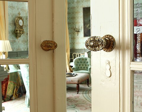 Ein Blick durch die einen Spalt geöffnete Tür in den grünen Salon im Residenzschloss in Oettingen