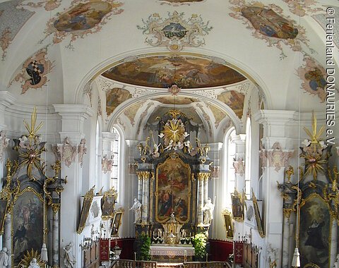 Blick von der Empore auf den hellen Altarraum und die beiden Seitenaltäre.