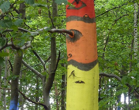 Ein bunt bemalter Baumstamm mit gemalten Augen