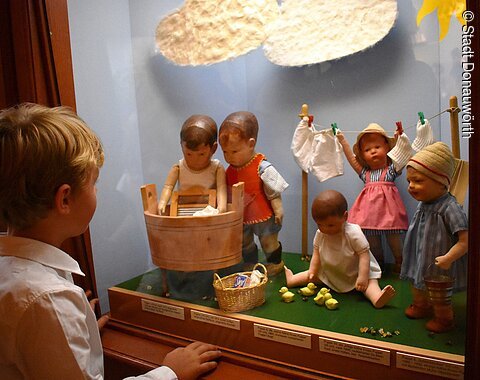 Ein Junge betrachtet eine Puppenszene im Käthe Kruse Puppenmuseum.