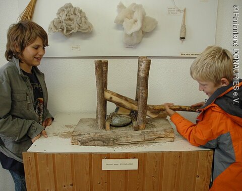 Zwei Jungen probieren das Model einer Steinsäge im Goldbergmuseum aus.
