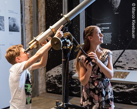 Zwei Kinder schauen durch ein Teleskop