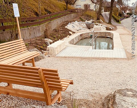 Sitzgelegenheiten am Kneippbecken in Allmannshofen mit daneben liegenden Kneippbecken.