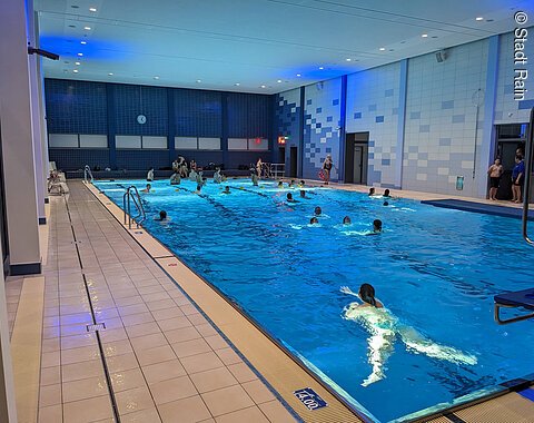 Hallenbad Rain Blick auf das beleuchtete Schwimmbecken mit Schwimmern im Hallenbad in Rain.