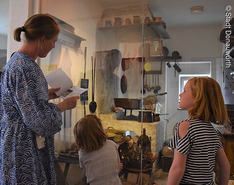 Familienführung im Heimatmuseum Donauwörth Eine Frau mit zwei Kindern sieht sich die alte Küche im Heimatmuseum an.
