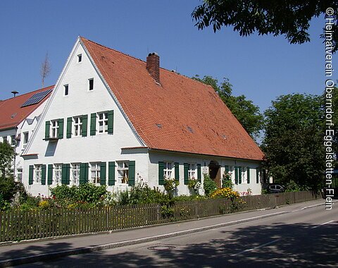Blick auf das alte Schulhaus mit seinen grünen Fensterläden.