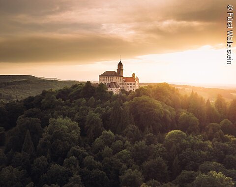 Schloss Baldern, erhöht im Wald liegend, bei Sonnenuntergang