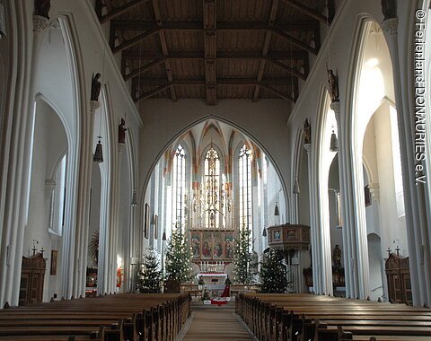 Innenansicht St. Salvator Nördlingen Blick in das lichtdurchflutete Innere mit dem Hauptaltar der von vier wegeschmückten Christbäumen umrahmt ist. Rechts vor dem Altar sieht man die Kanzel.