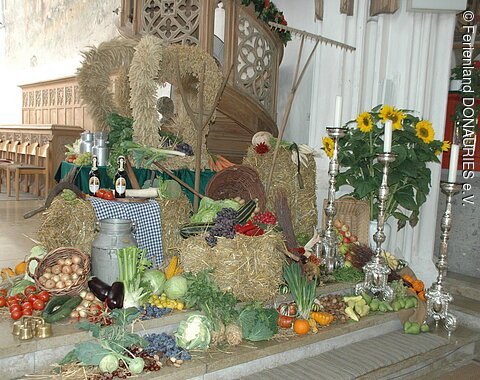 Erntedank St. Salvator Nördlingen Die Erntedankdekoration mit zur Krone gebundenem Getreide und verschiedenem Obst und Gemüse.