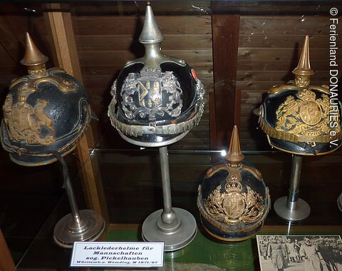 Fünf verschiedene Pickelhauben in einer Vitrine