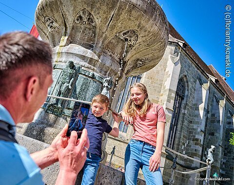 Zwei Kinder werden vor dem Kriegerbrunnen in Nördlingen von ihrem Vater fotografiert.