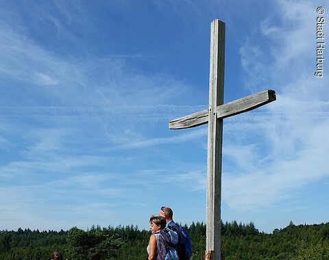 Wanderer stehen am Kreuz auf dem Bockberg