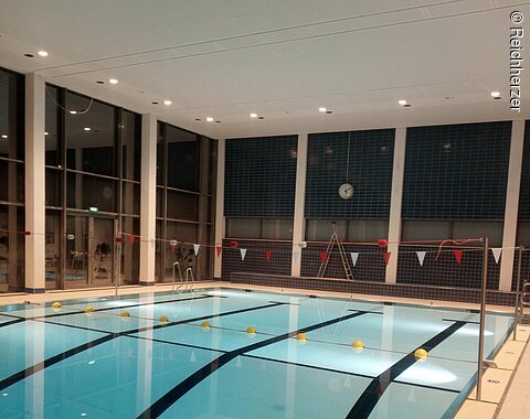 Blick auf das beleuchtete Schwimmbecken am Abend