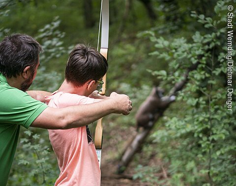 Ein Mann erklärt einem Kind das Bogenschießen.
