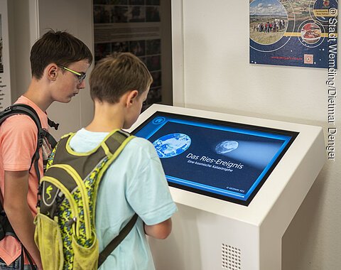 Kinder schauen sich die Ries-Animation in der Geopark-Infostelle an.