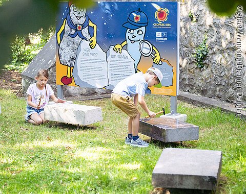 Kinder spielen an der Kinder-Erlebnisstation am Kreuzgraben mit Klangsteinen.