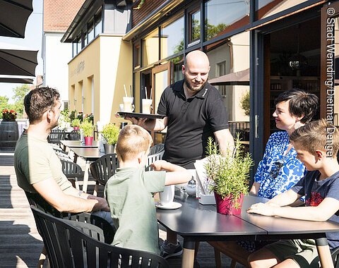 Eine Familie isst auf der Terrasse beim Lieblingsgrieche in Wemding.