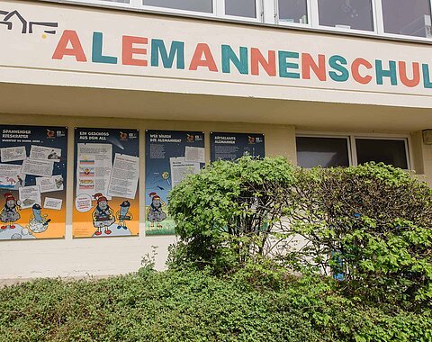 An einer Hauswand sind vier Informationstafeln für Kinder angebracht. Darüber steht in Großbuchstaben "Alemannenschule".