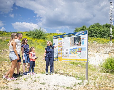 Eine Geopark Ries Führerin zeigt einer kleinen Gruppe Personen eine Informationstafel.