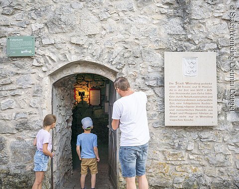 Vater betrachtet den Eingang des Folterturms mit seinen zwei Kindern.