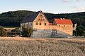 Ein altes Gebäude das von einem Weizenfeld umgeben ist.