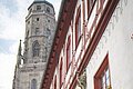 Altstadt Nördlingen mit Blick auf Daniel Fachwerkhaus mit roten Fensterrahmen und Blumenkästen, daneben ein Kirchturm.