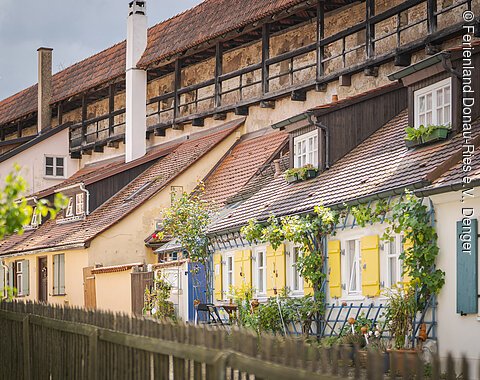 Reihen von kleinen, bunten Häusern mit Schrägdächern und Pflanzen an den Fassaden.