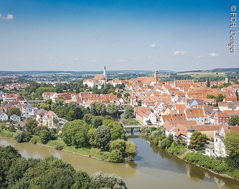 Stadtansicht von Donauwörth mit den Flüssen Donau und Wörnitz, roten Dächern und Kirchturm, umgeben von grüner Landschaft.