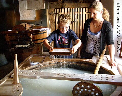 Papierschöpfen Eine Frau schöpft mit einem Jungen Papier