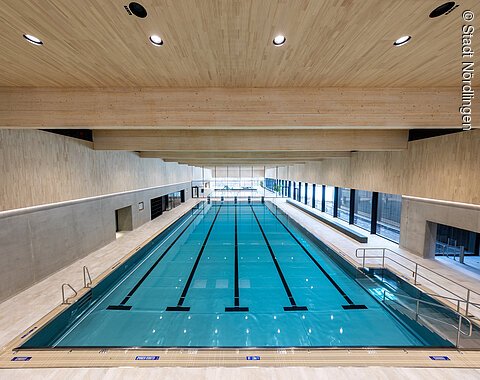 Blick auf das Schwimmbecken im Kraterbad in Nördlingen Innenaufnahme eines Schwimmbeckens mit Holzdecke und großen Fenstern an der rechten Seite
