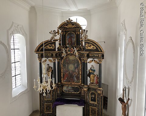 Barocker Altar mit Gemälden, Statuen und vergoldeten Verzierungen in weißem Kirchenraum mit Fenstern und Kronleuchter in der Allerheiligenkapelle in Rain.