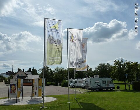 Wohnmobilstellplatz mit Geopark Infostelle Monheim Die Geopark Infostelle mit Flaggen und im Hintergrund die Wohnmobile auf dem Wohnmobilstellplatz in Monheim.