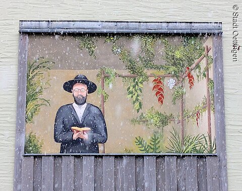 Wandbild eines Mannes mit Hut und Brille, der ein Buch hält, umgeben von Pflanzen.