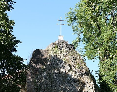 Mangoldfelsen in der Promenade Ein hoher Felsblock trägt ein Kreuz obenauf und eine Inschrifttafel.