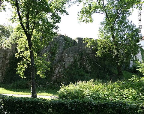 An einen großen Felsblock schließen sich die Mauern einer ehemaligen Burg an.