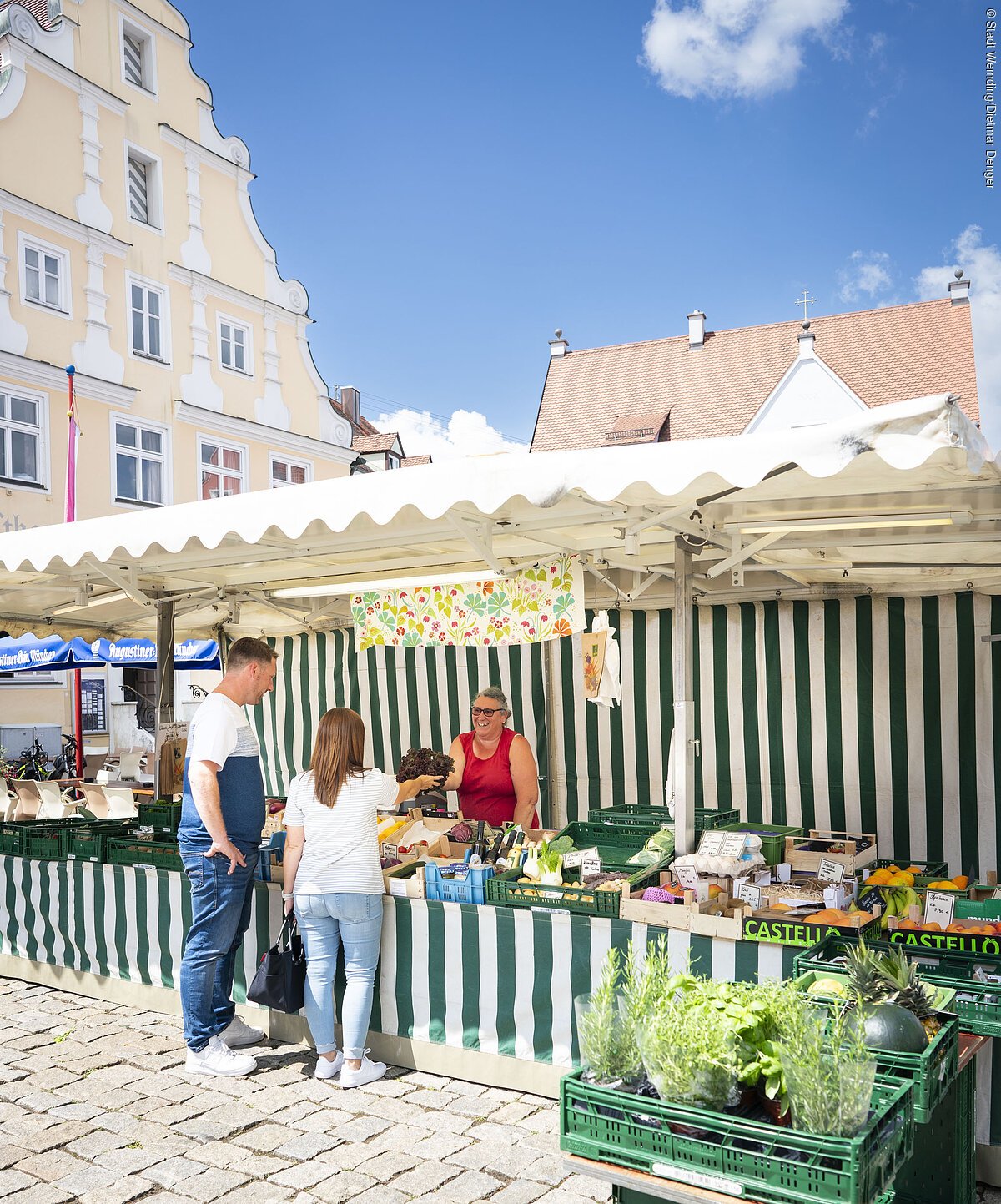 Ein Paar kauft am Wochenmarkt in Wemding bei einem Verkaufsstand ein.
