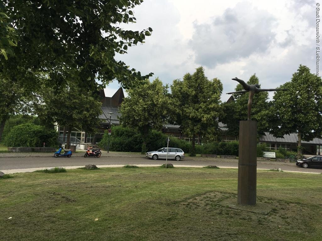 Das Bild zeigt eine Statue im Stauferpark darum sehr viel grün mit Sträuchern, Bäumen usw.